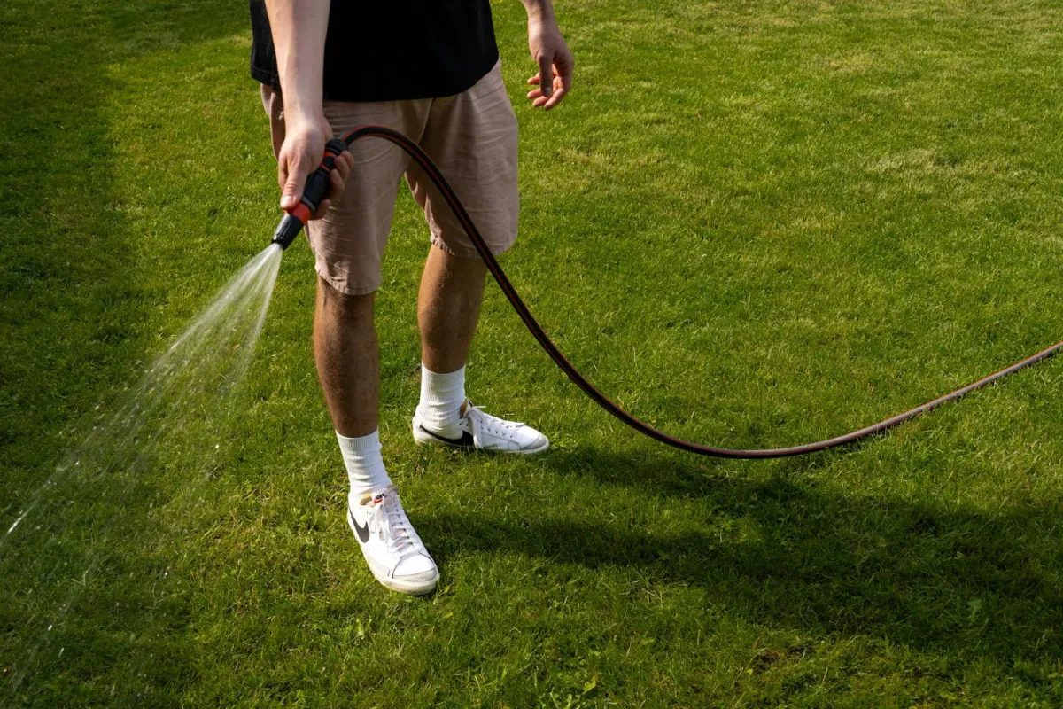 Hand holding a smartphone displaying a smart irrigation app to control sprinklers remotely